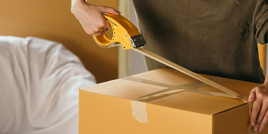 close up view of a person packing a box with tape